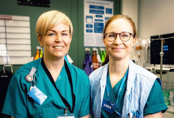 kaksi naishoitajaa hymyilee suoraan kameralle