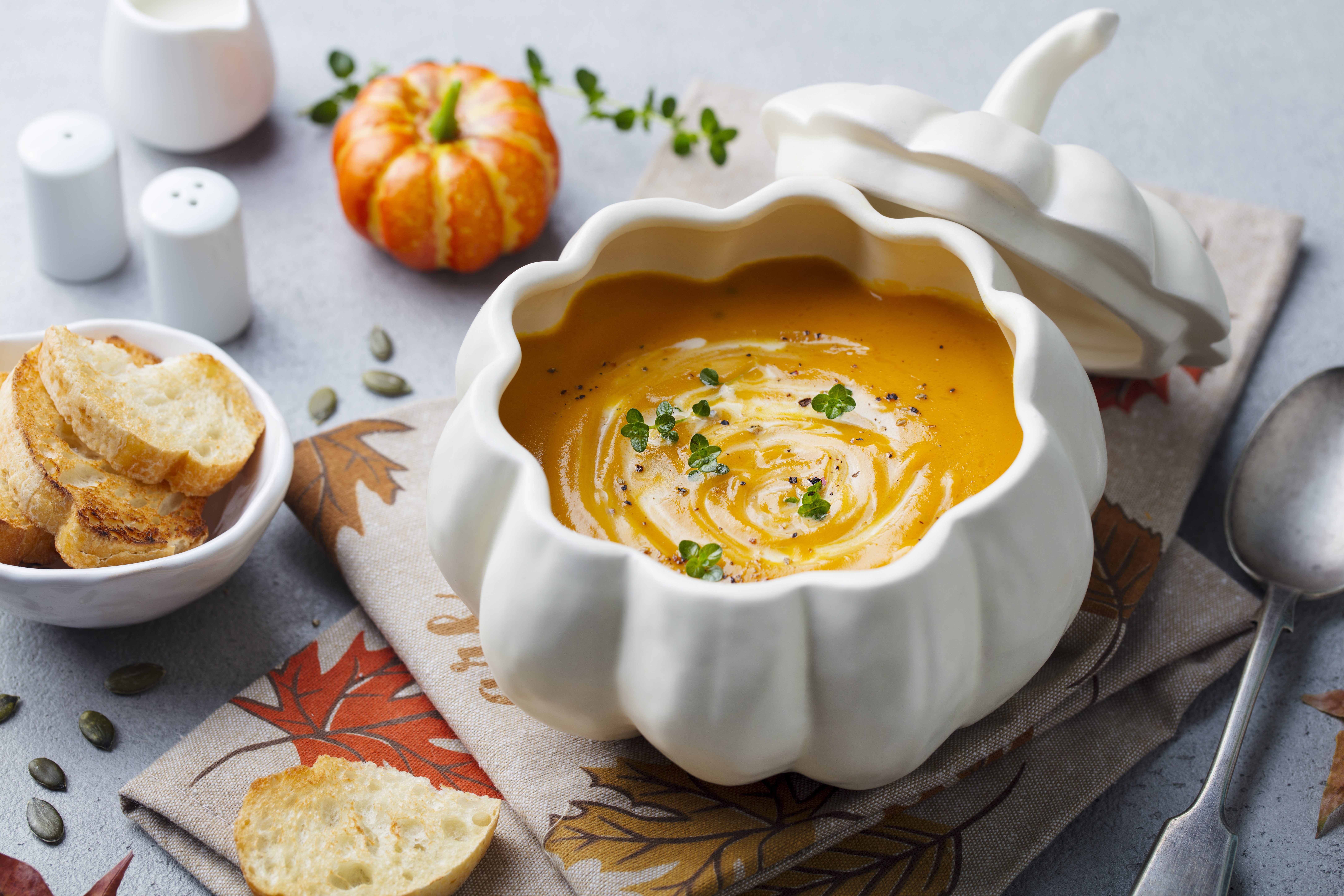 Pumpkin and carrot cream soup in creative bowl. Grey background. Close up.