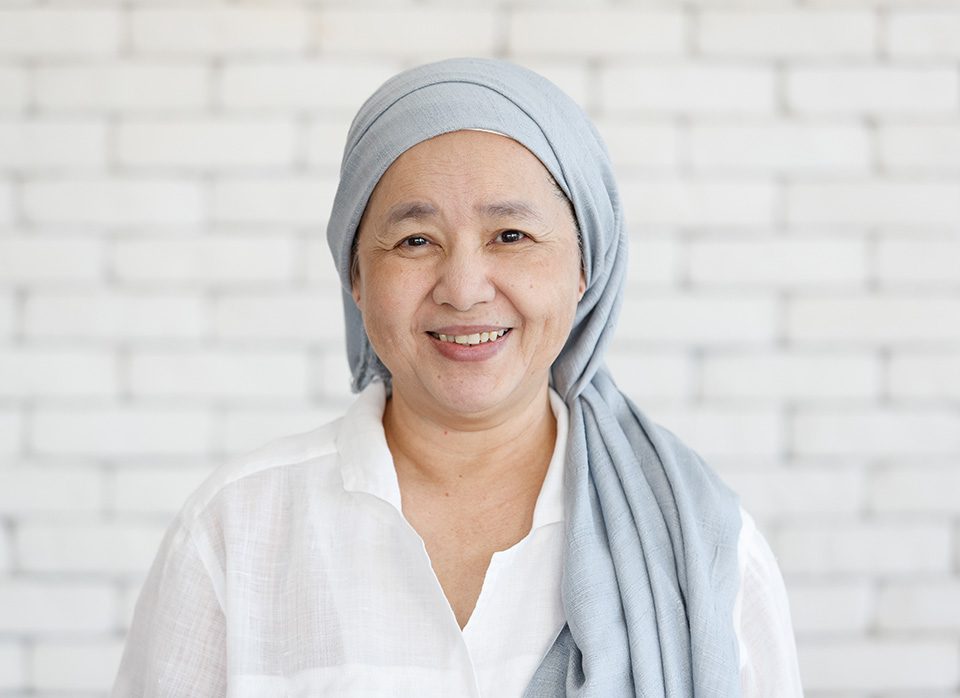 Portrait of an Asian woman with a clothe covered head and smile with happiness to the camera. Concept of a cancer patient with effected of chemo treatment but still feel hope and strength, Portrait of an Asian woman with a clothe covered head and smile 
