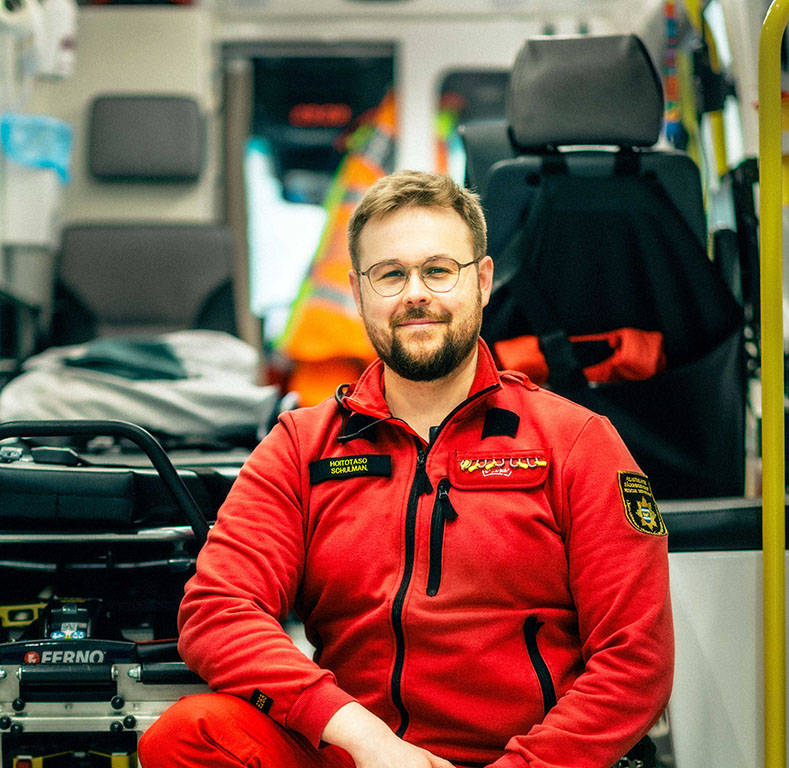 Ensihoitaja istuu ambulanssin edessä
